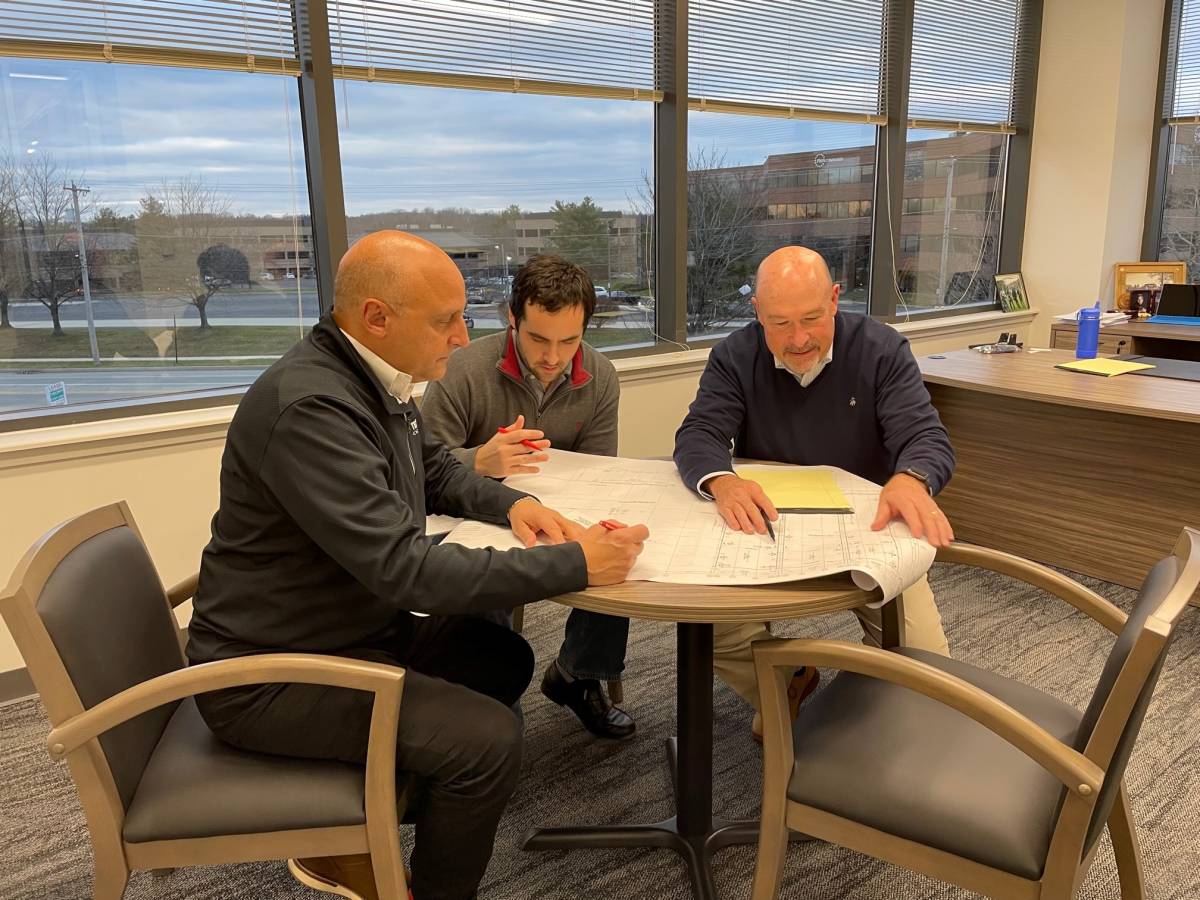 three team member gather around a desk to plan