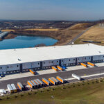 back view of warehouse with trucks and second warehouse in the distance