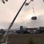 view of crane lifting equipment onto a roof