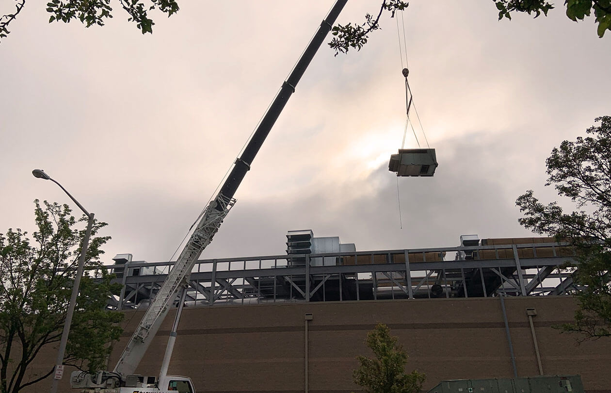 view of crane lifting equipment onto a roof