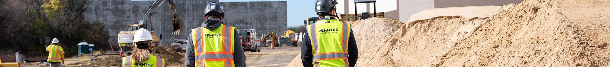 group of 3 penntex employees walking in construction site about