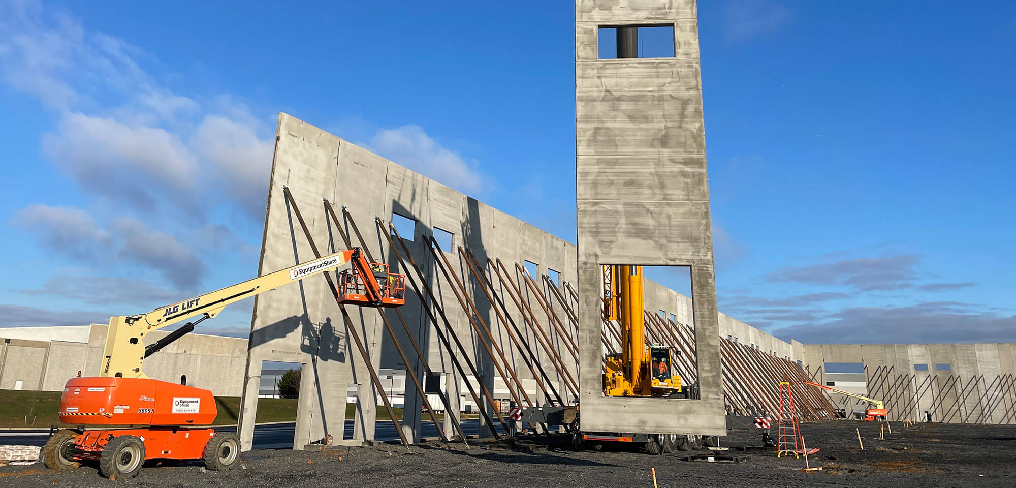 large crane putting up support wall on construction site