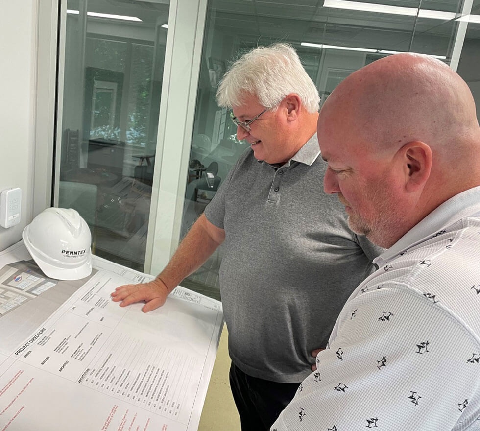 penntex employees smiling while reviewing blueprints
