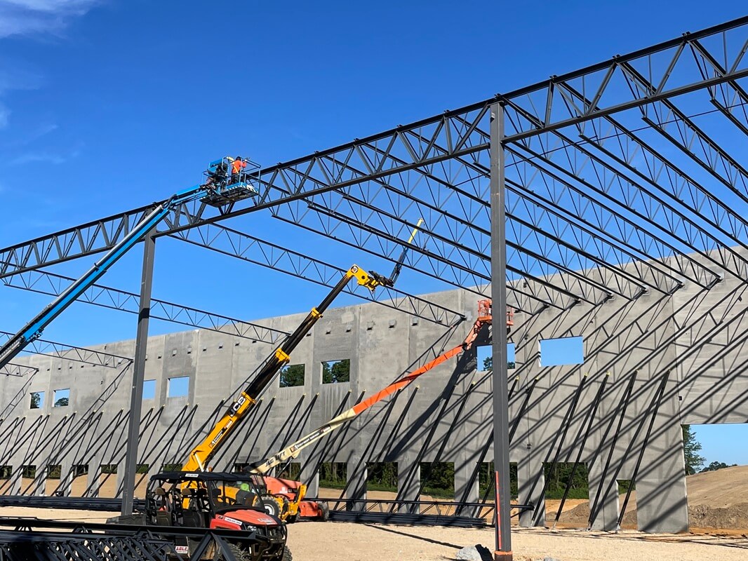 wide view of multiple workers in construction lifts working on a building