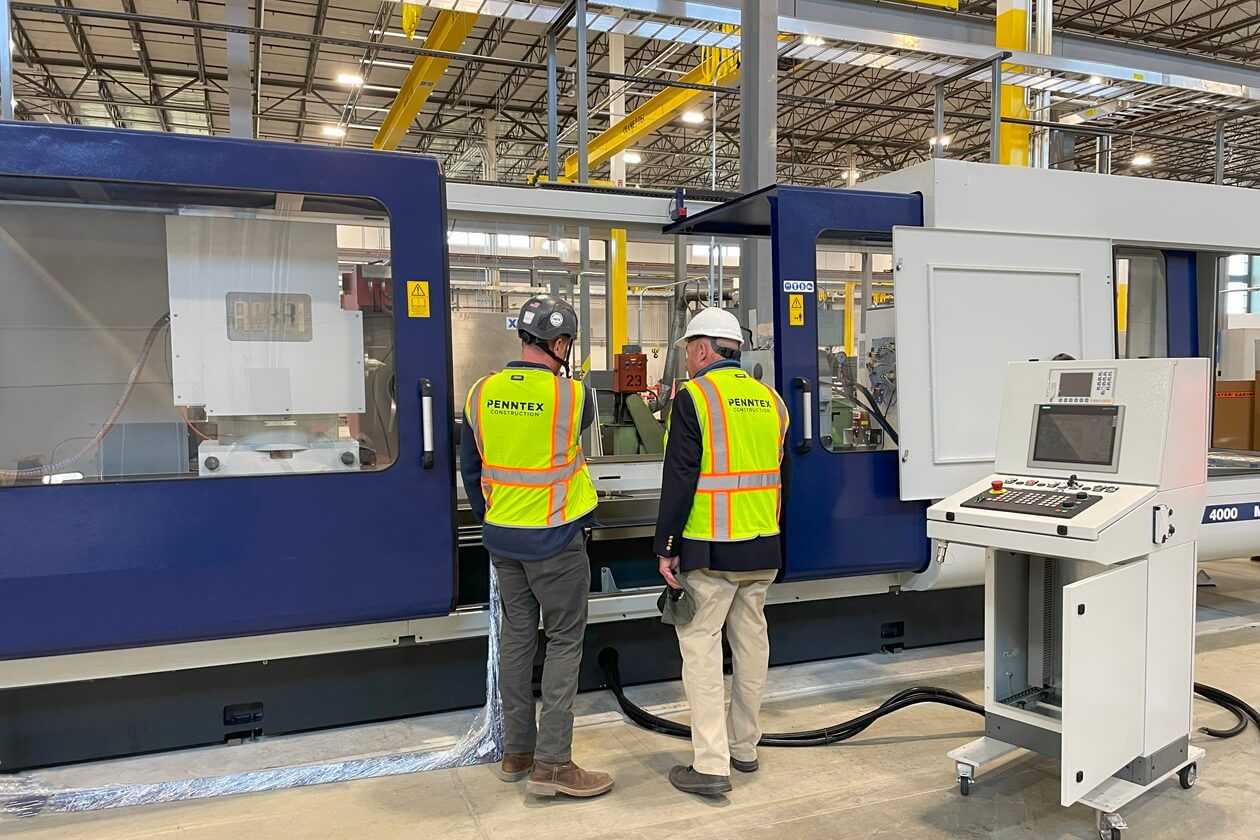 Penntex Team Members on Production Floor Looking at Equipment
